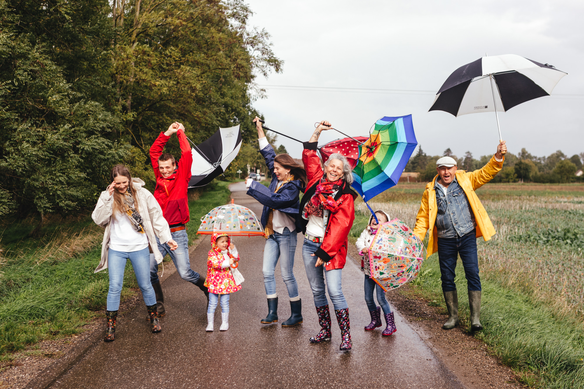 Une famille joyeuse sous la pluie avec des parapluies et vestes colorés